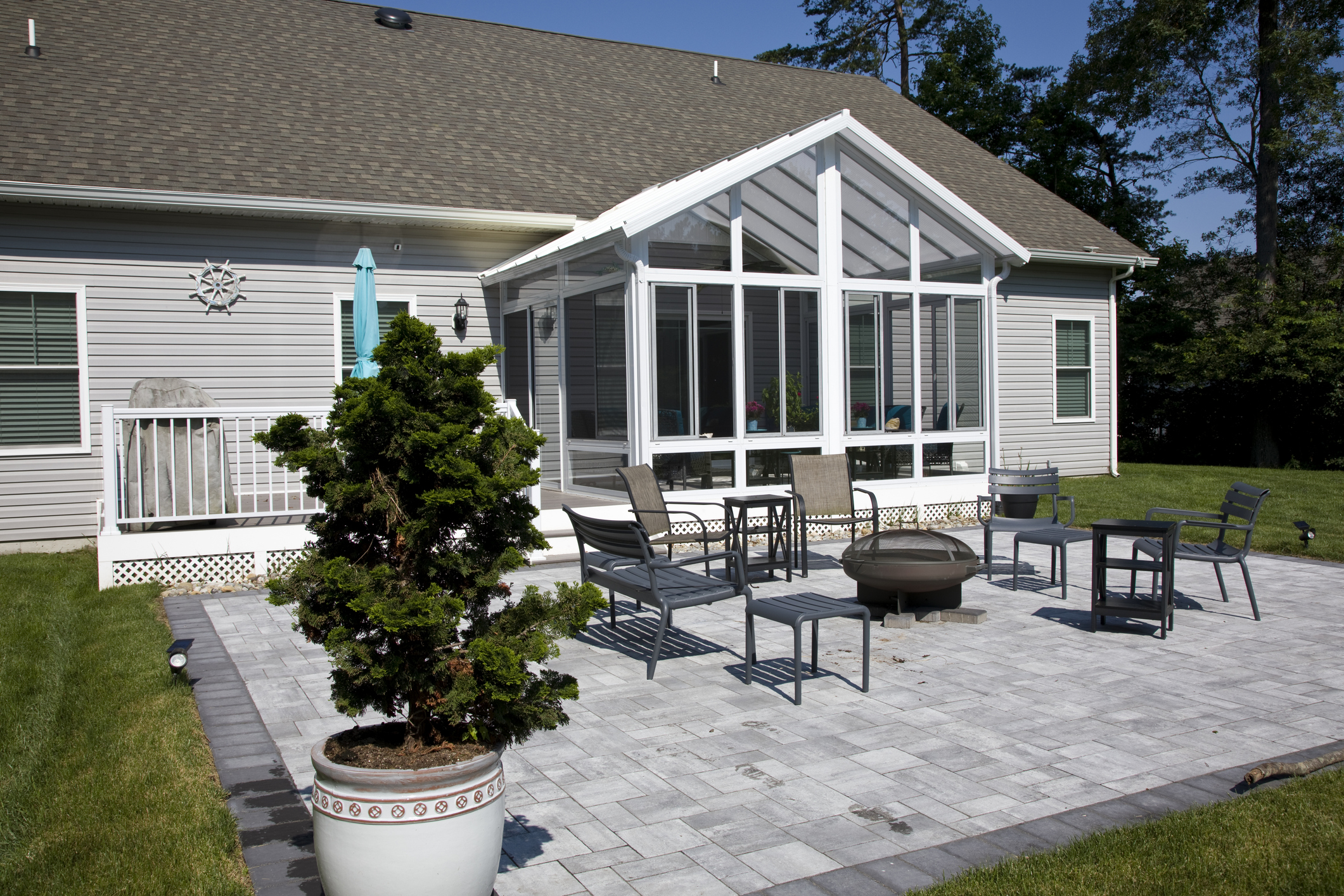 Back yard exterior of home with sun room, patio, and manicured lawn in the suburbs.
